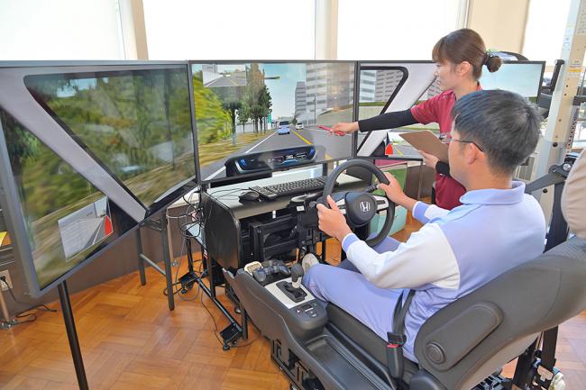 療法士が運転シミュレーターを用いた練習を支援する場面