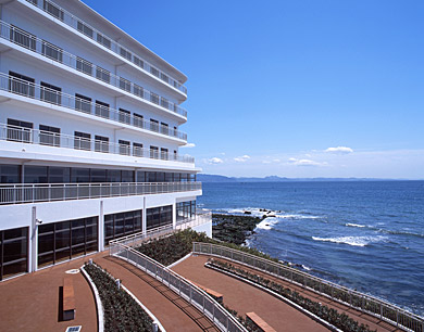公式入院案内に掲載された、海を望むパシフィックホスピタルの病棟外観とリハビリ庭園