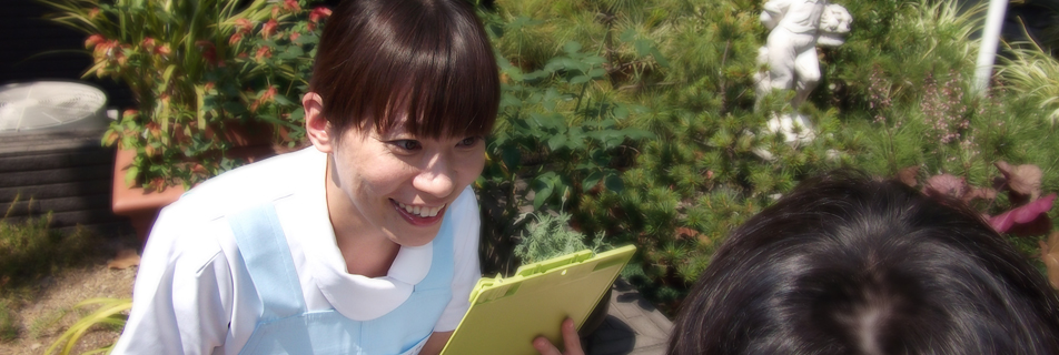 緑のある屋外で患者と向き合う看護師