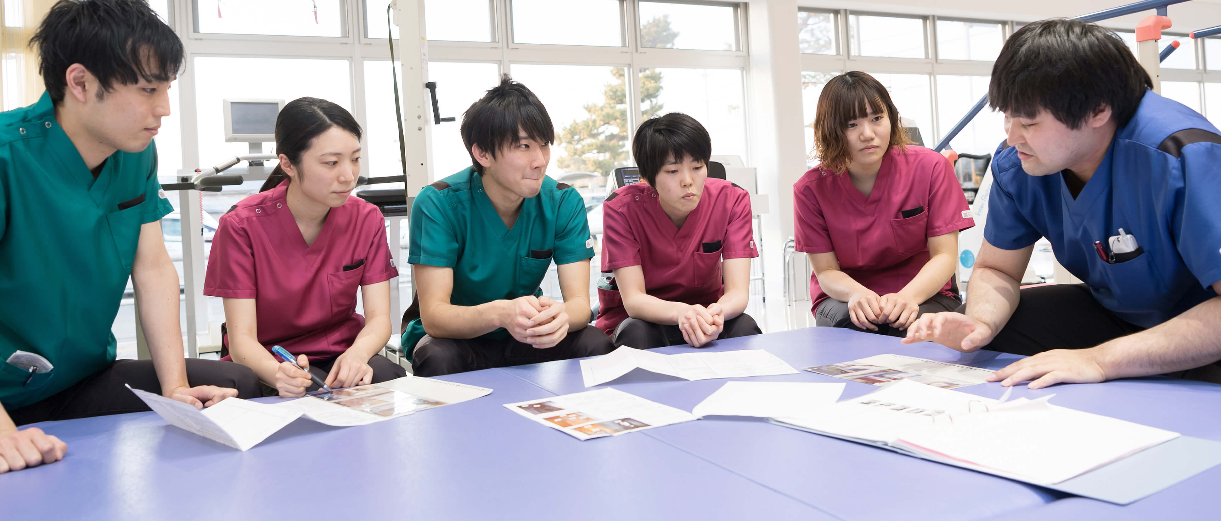 公式トップに掲載されたリハビリスタッフが連携して話し合う場面