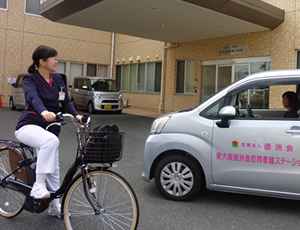 自転車と訪問看護車両を使うスタッフ