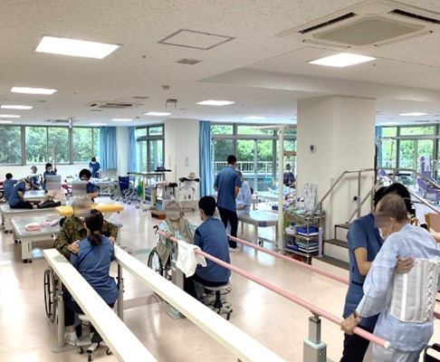 スタッフと利用者がリハビリテーションを行う明るい訓練室
