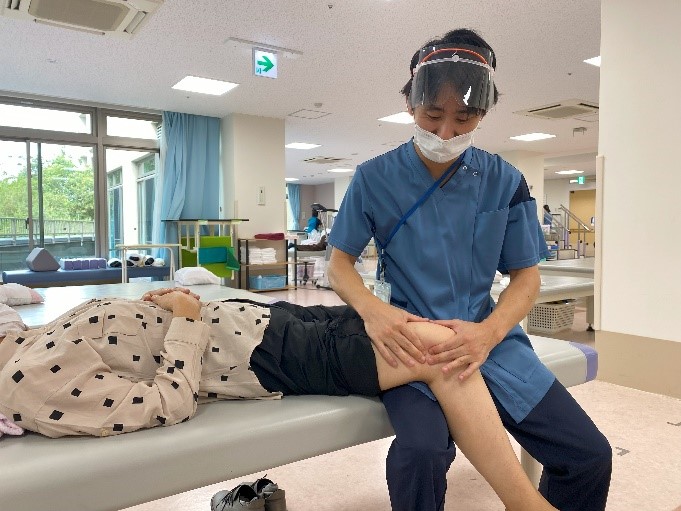 スタッフが利用者の膝の状態を確認するリハビリテーション