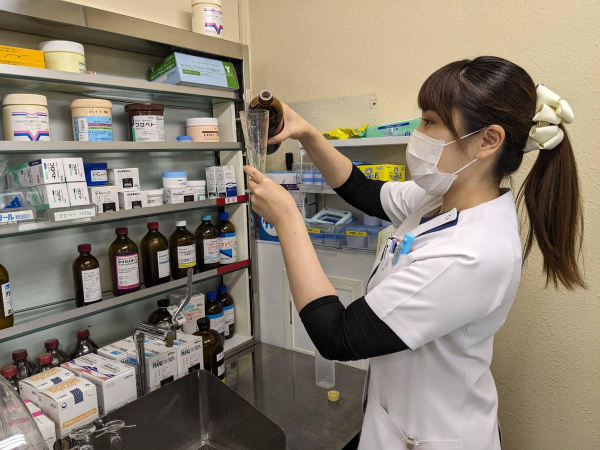 薬品棚の前で調剤業務を行うスタッフ