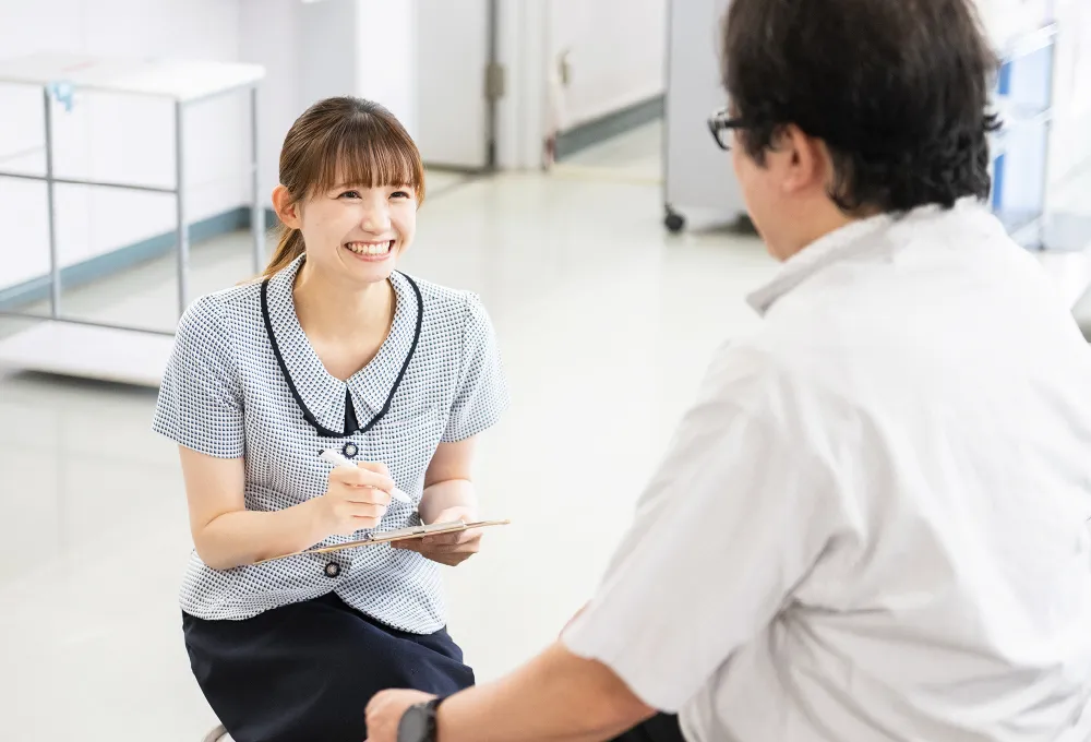 公式トップに掲載される、院内で職員が患者と対話する様子