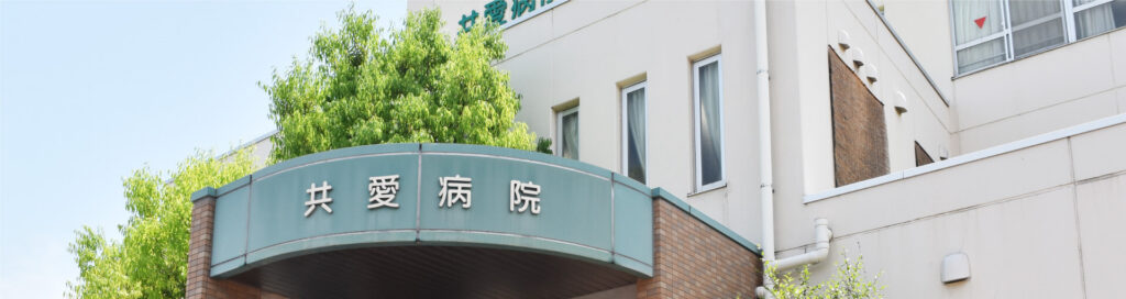共愛病院の入口にある病院名表示と建物