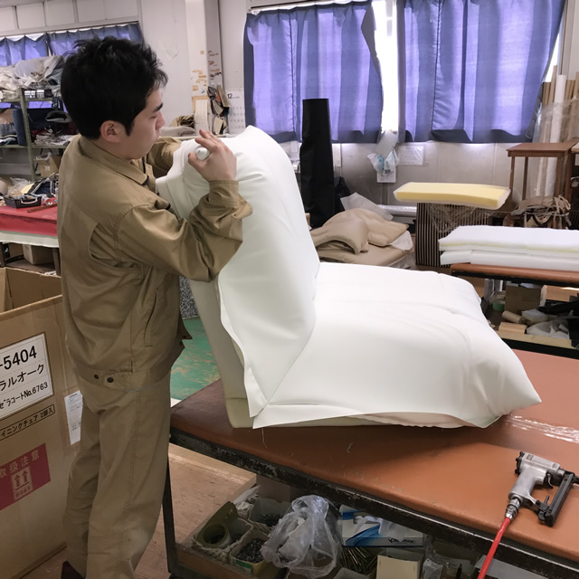 ソファーに張地を仕上げる職人