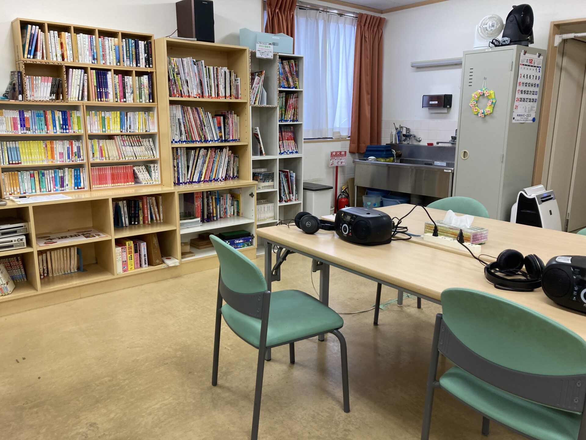 公式チーム七生ページに掲載された、書籍・音響機器・テーブルのある活動スペース