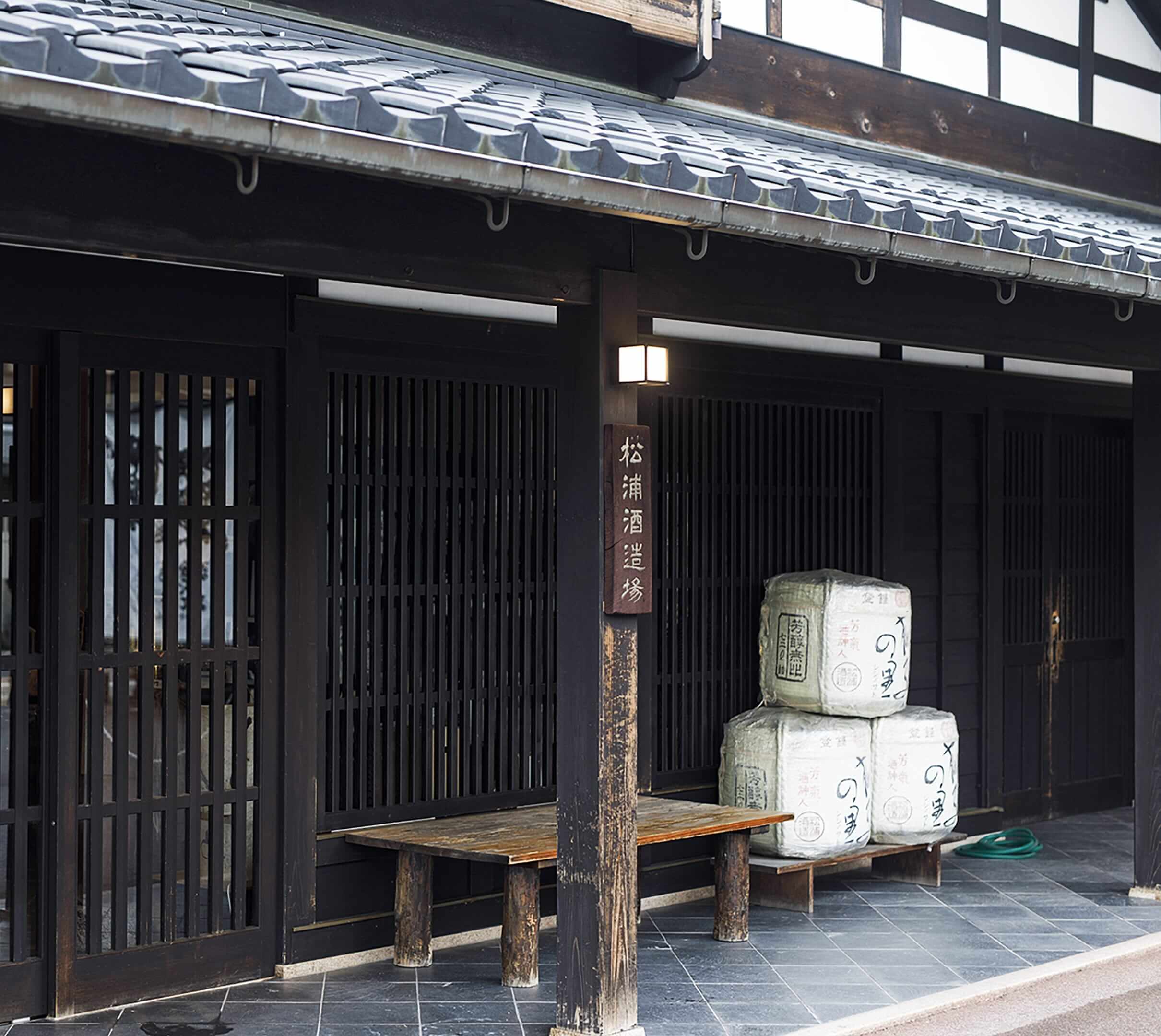 公式トップの会社案内に掲載された酒蔵の格子戸と酒樽
