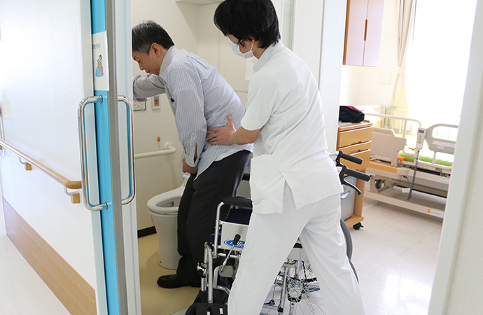 療法士が利用者の移動動作を支援する病室内の様子