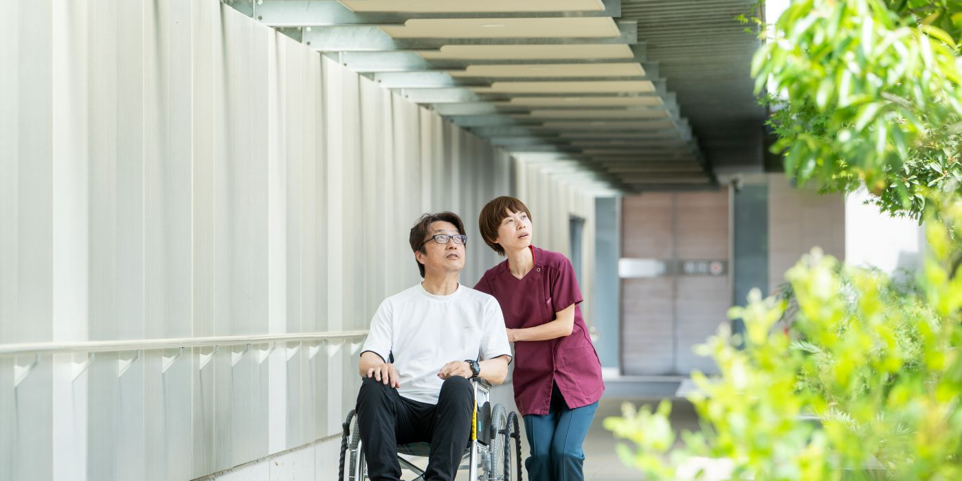 院内の回廊で車いす利用者に寄り添う職員