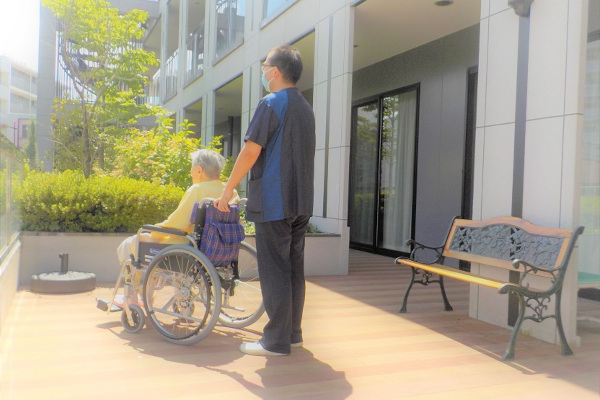 テラスで車椅子利用者を支援するスタッフ