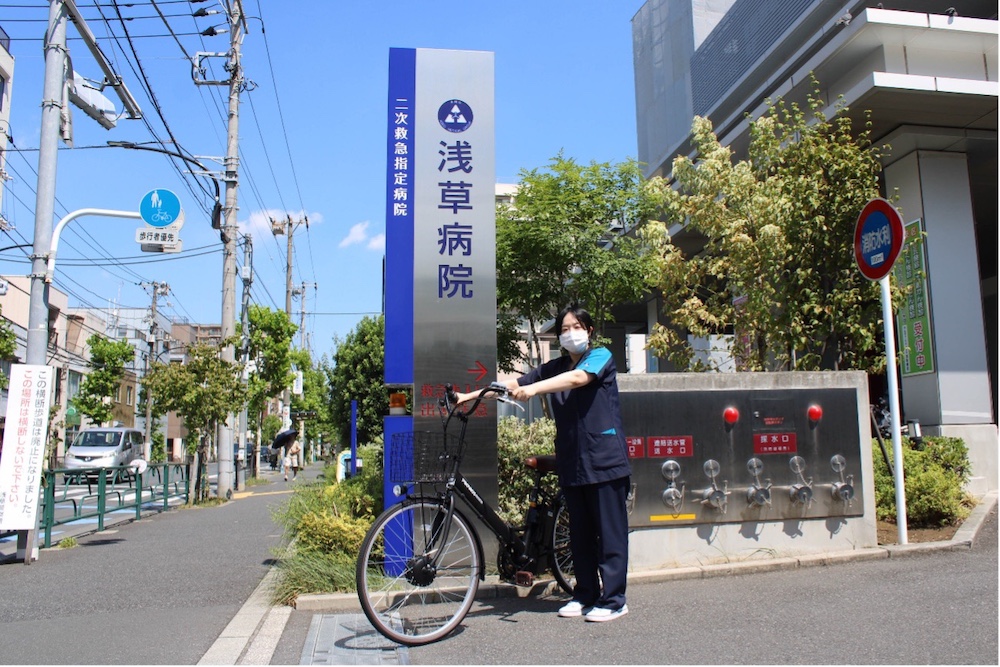 自転車で在宅支援に向かう医療スタッフと病院入口