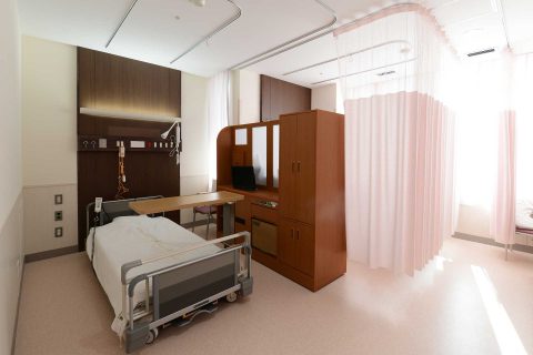 ベッドと収納、カーテンを備えた個室病室