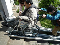 屋外で車いす利用者をスタッフが支援する様子