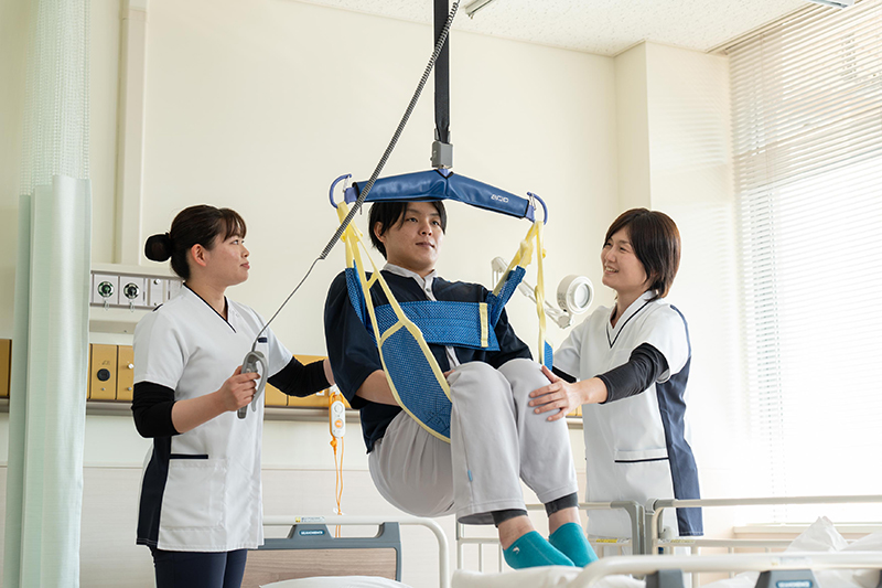 病室でリフトを使い看護師が患者を支援する場面