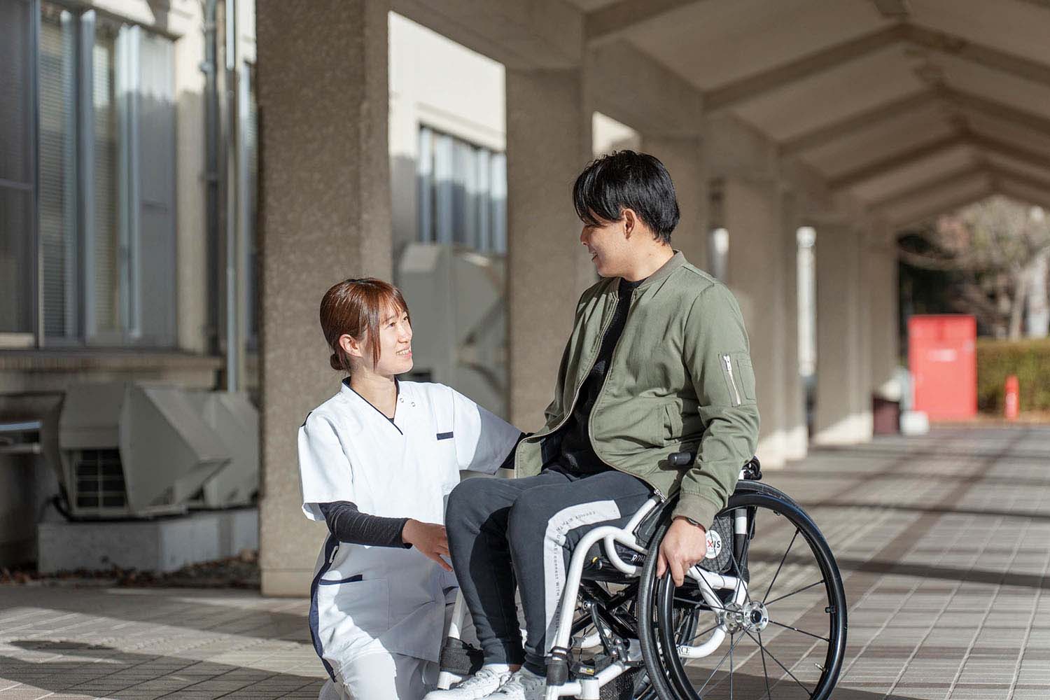 玄関前で車いす利用者に寄り添う看護師