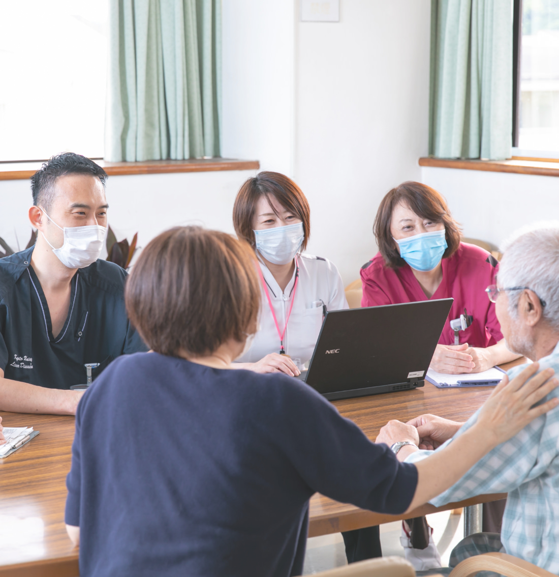 患者と家族を囲み対話する医療スタッフ
