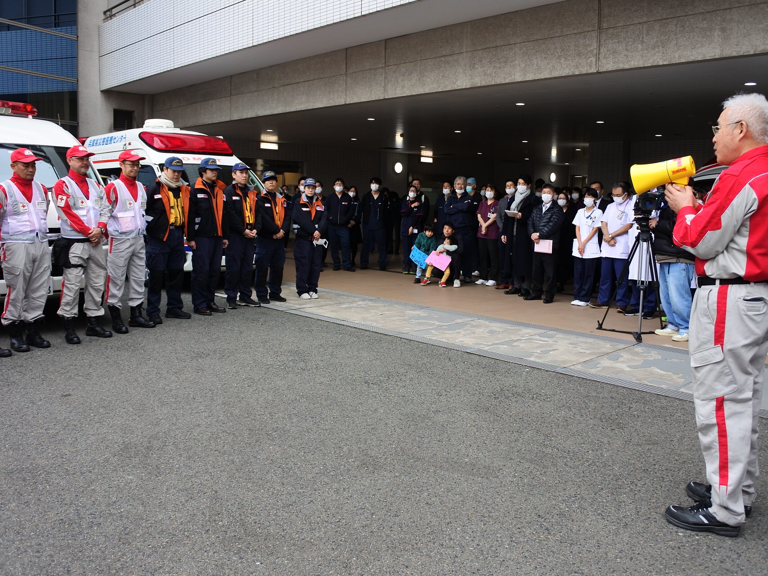 救護車両前で説明を受ける赤十字救護班と院内スタッフ