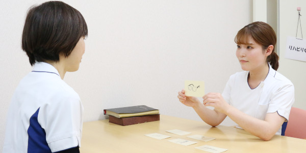 療法士と利用者がカードを用いる言語聴覚療法の様子