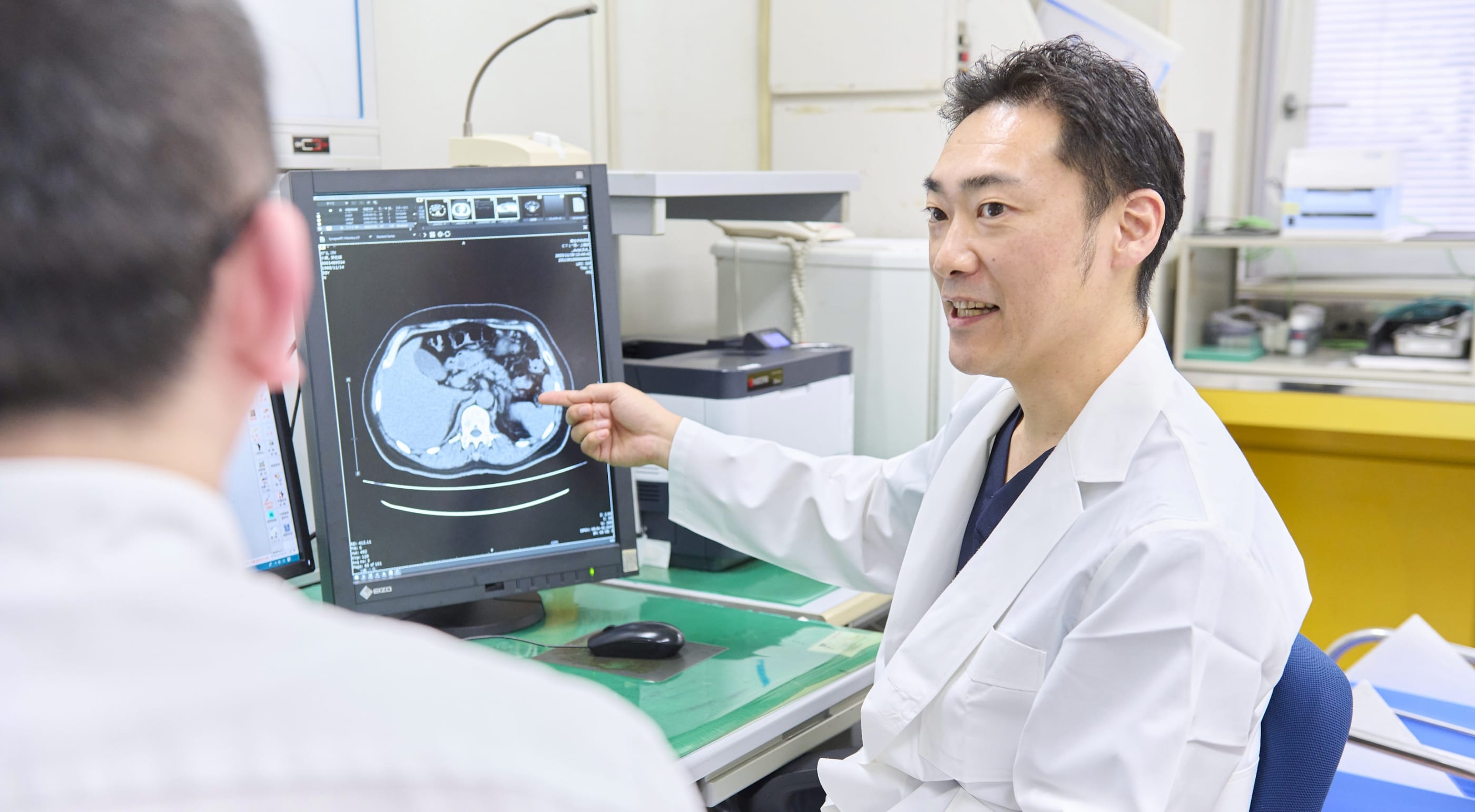 診察室で画像を見ながら患者に説明する医師