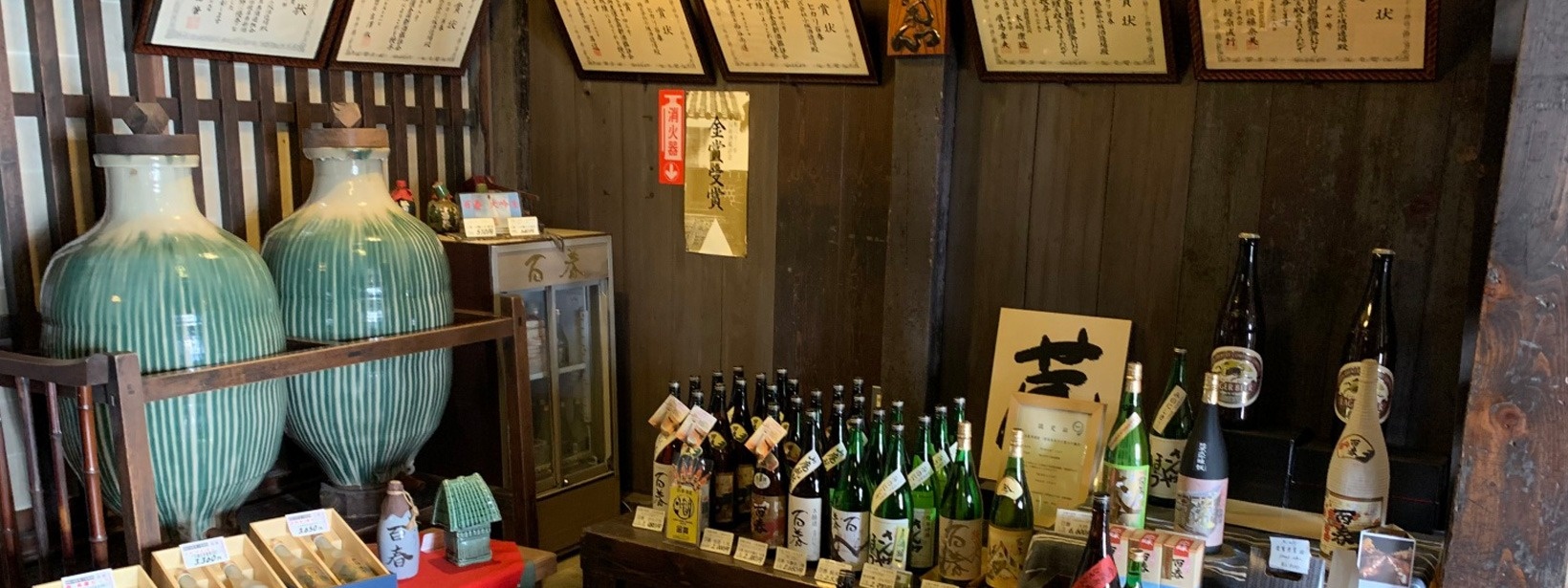 公式トップに掲載された酒瓶と甕が並ぶ蔵の直売コーナー