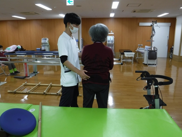 スタッフが利用者の歩行訓練を支援する様子