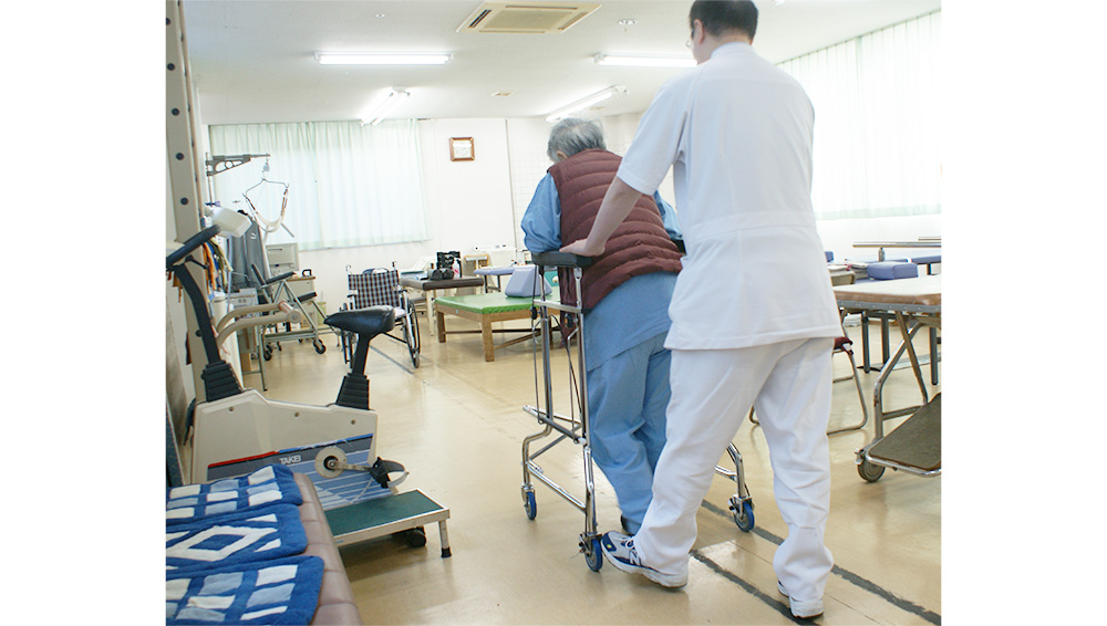 理学療法士が歩行器を使う利用者を支援する様子