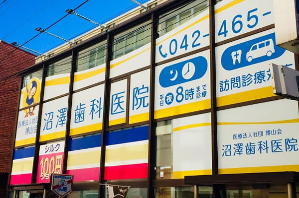 沼澤歯科医院の名称と訪問診療案内を掲げた建物外観