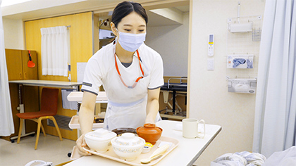療養生活の食事をベッドサイドへ届けるスタッフ