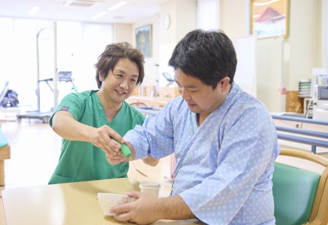 スタッフが患者の食事動作を支援する様子