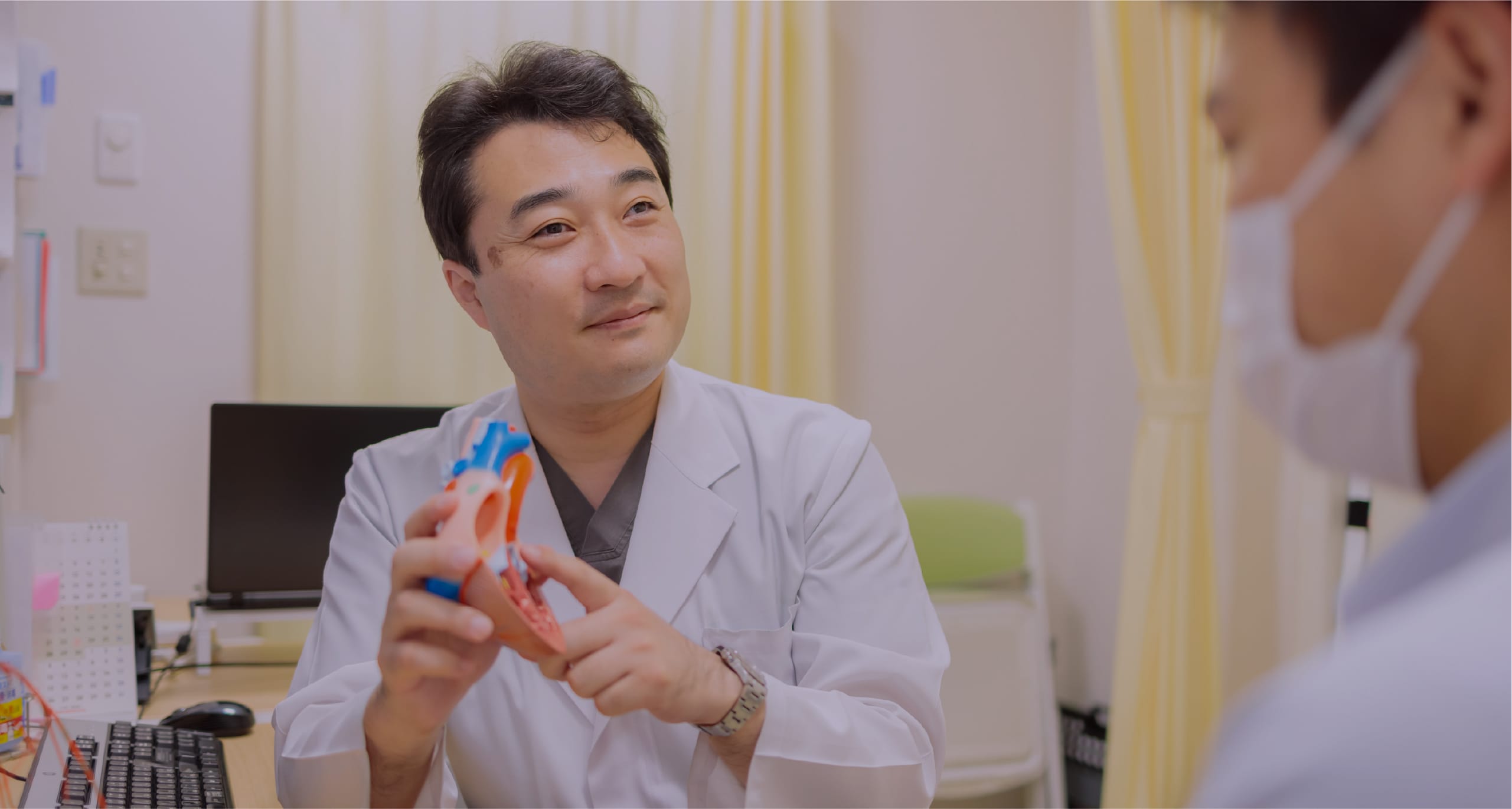 医師が心臓模型を示して患者に説明する様子