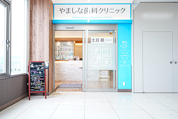 公式トップ掲載の、医院名を掲げるやましな歯科クリニック入口